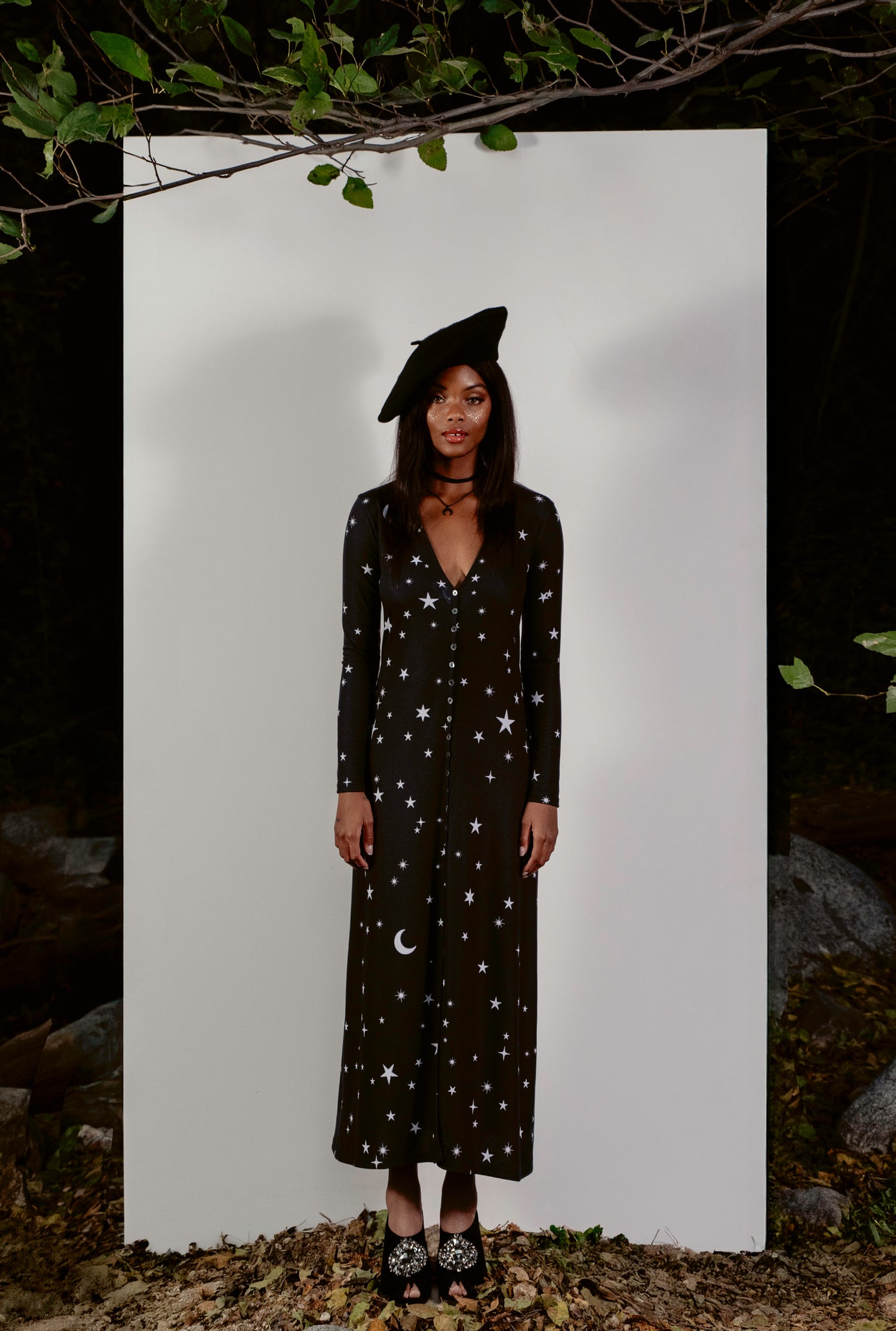 Person wearing a black dress with star and moon patterns on a white background