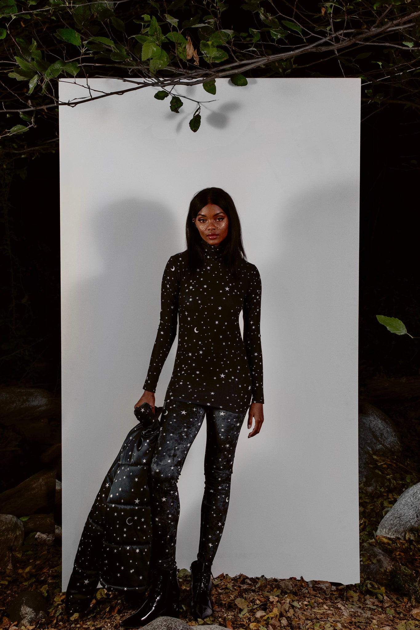 Person wearing a black outfit with star patterns against a white background outdoors.