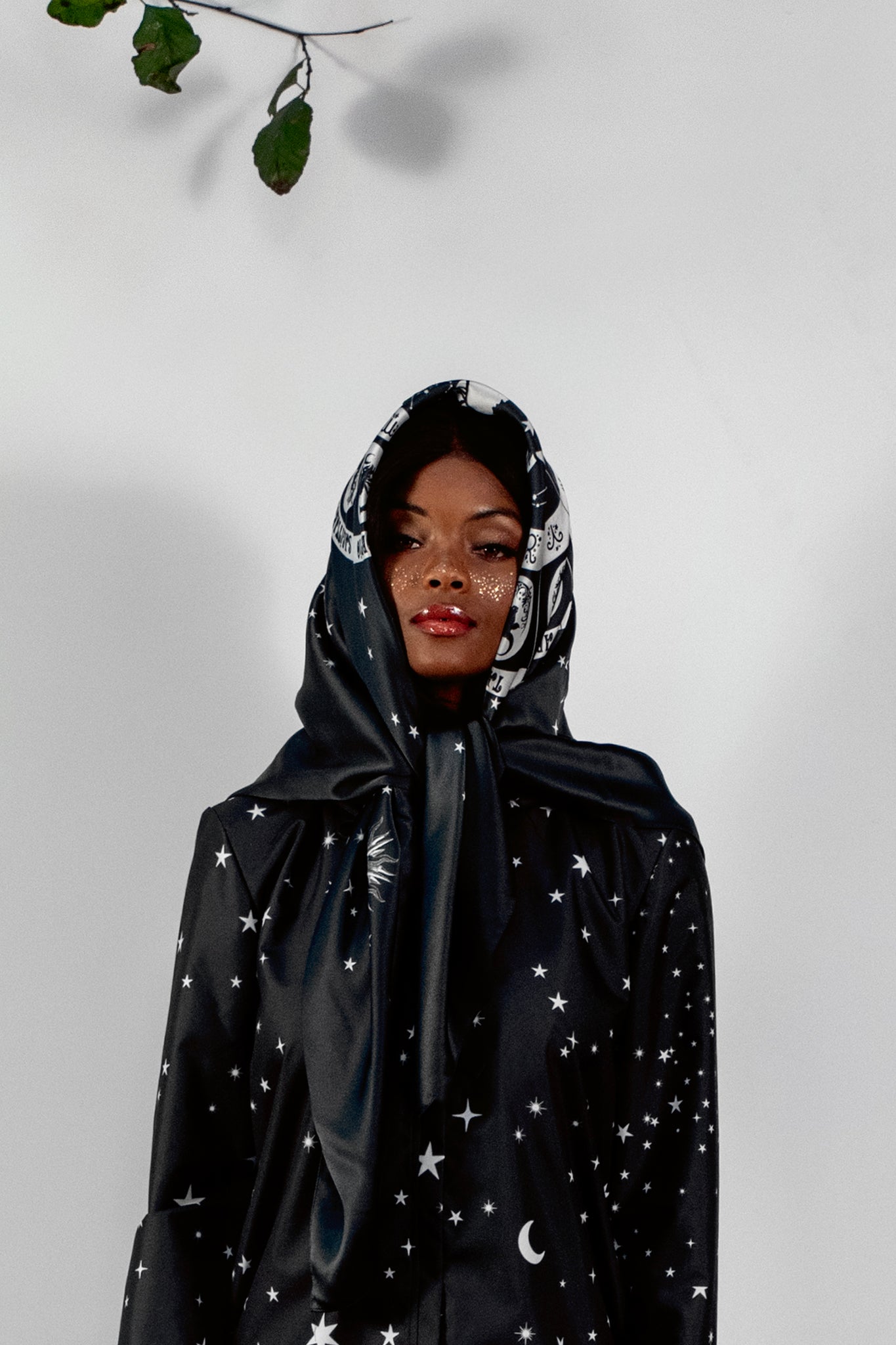 Person wearing a scarf with star and moon patterns on a plain background