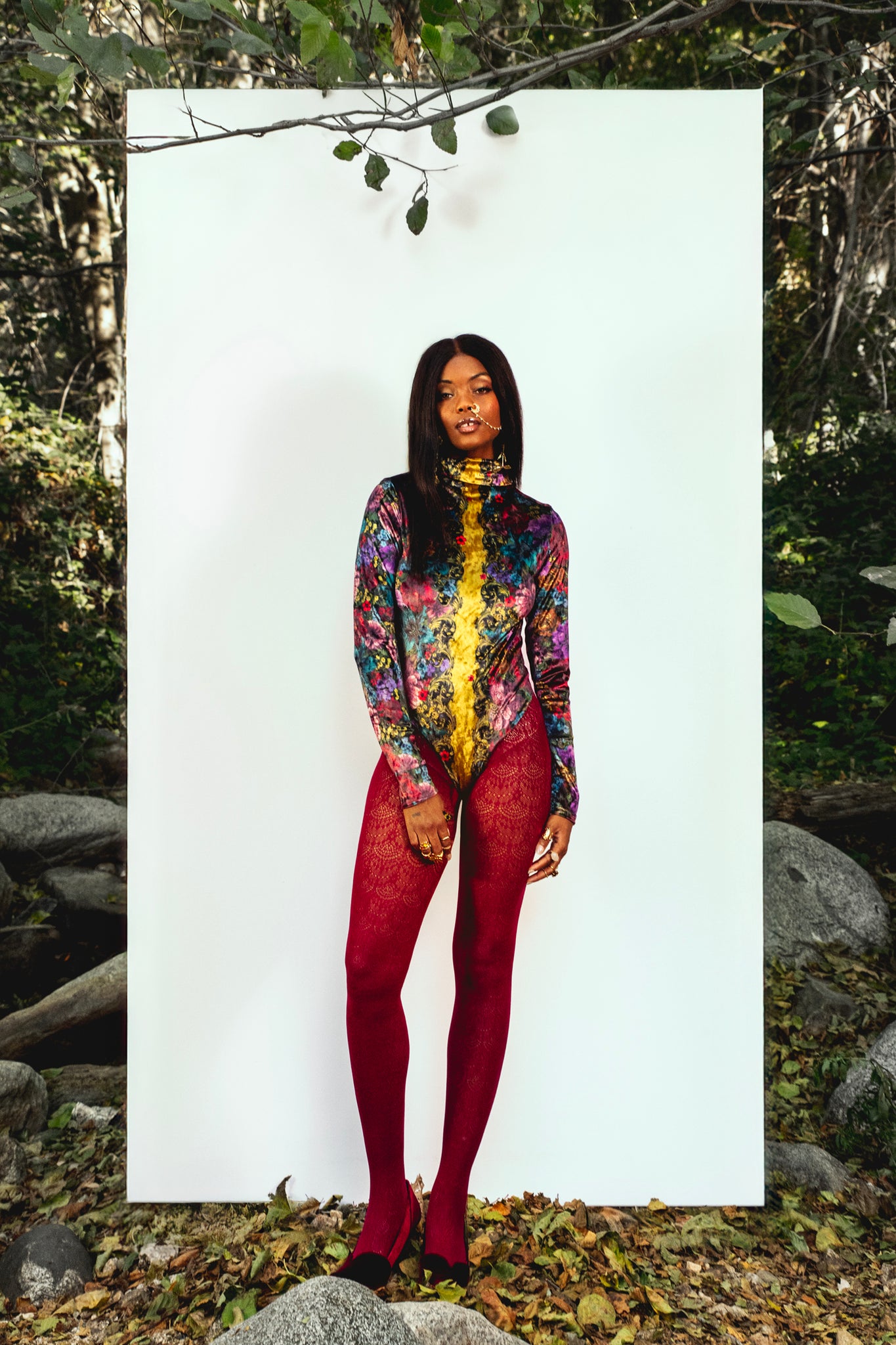 Person wearing a colorful bodysuit with red tights standing against a white background