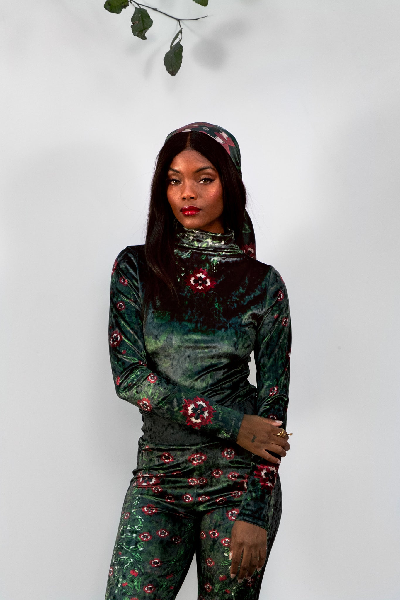 Woman wearing a green floral velvet bodysuit against a white background
