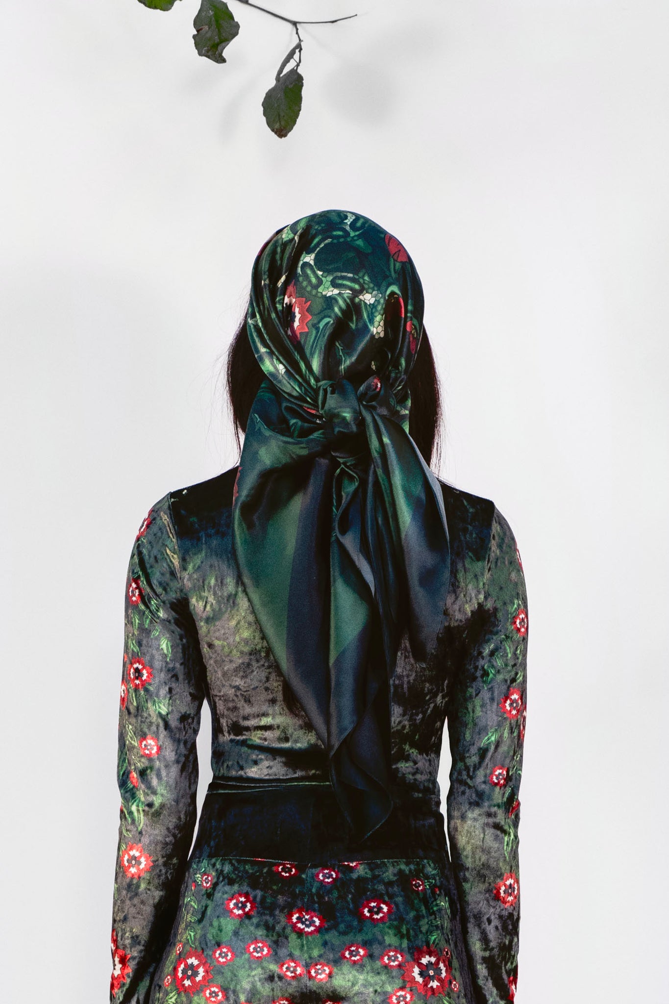 Person wearing a dark green floral scarf  on a white background