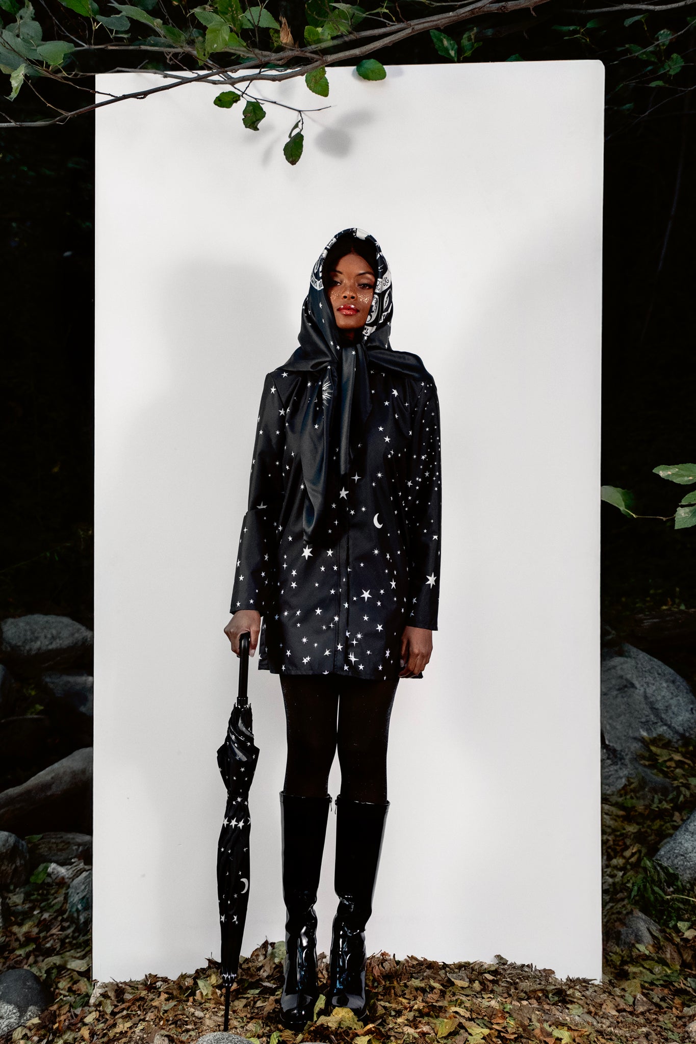 Person wearing a black raincoat with star patterns standing against a white background.